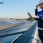 Technician inspecting rooftop solar panels on a large commercial metal roof while using a laptop and wearing a white safety helmet and blue work uniform under a clear blue sky. The image highlights professional solar panel inspection, maintenance, and renewable energy installation. The website name "voltixpowers.com" appears in the top-left corner.